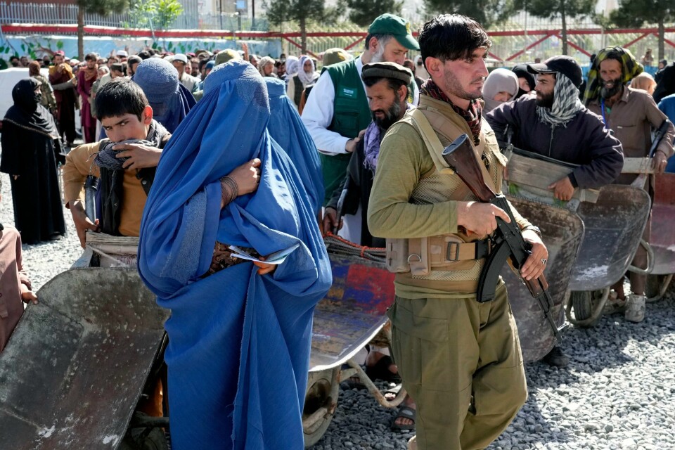 En soldat fra Taliban står vakt mens en gruppe mennesker venter på å få matrasjoner utdelt fra en humanitær gruppe, i Kabul, Afghanistan. AP Photo/Ebrahim Noroozi Forbudene er mange og det er ikke lett å være afghansk kvinne under Taliban-styret. Her står folk i kø for å få delt ut matrasjoner av en humanitær hjelpeorganisasjon i Kabul i slutten av april. Foto: Ebrahim Noroozi / AP / NTB