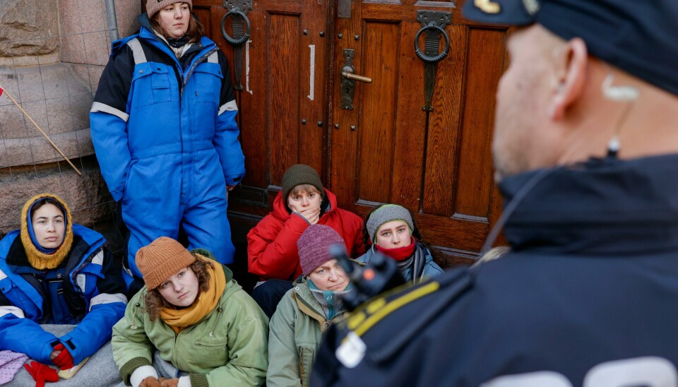 Politi og aksjonister ved en av inngangene til Finansdepartementet. Aksjonister fra Natur og ungdom og Norske Samers Riksforbund Nuorat fortsetter tirsdag sin demonstrasjon i regjeringskvartalet. Bakgrunn for aksjonen er at vindturbinene på Fosen, som Høyesterett har sagt at er ulovlige, ikke er revet. Aksjonister fra Natur og ungdom og Norske Samers Riksforbund Nuorat fortsetter tirsdag sin demonstrasjon i regjeringskvartalet. Tirsdag er også inngangene til Finansdepartementet sperret. Foto: Alf Simensen / NTB