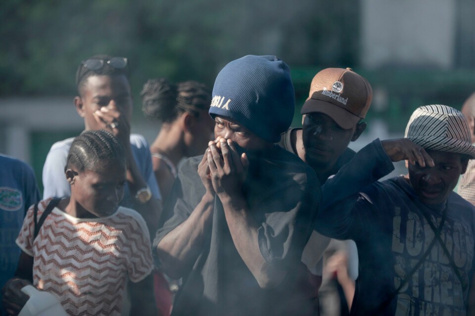 Forbipasserende betrakter likene av bandemedlemmer som er lynsjet i Port-au-Prince. Foto: Odelyn Joseph / AP / NTB