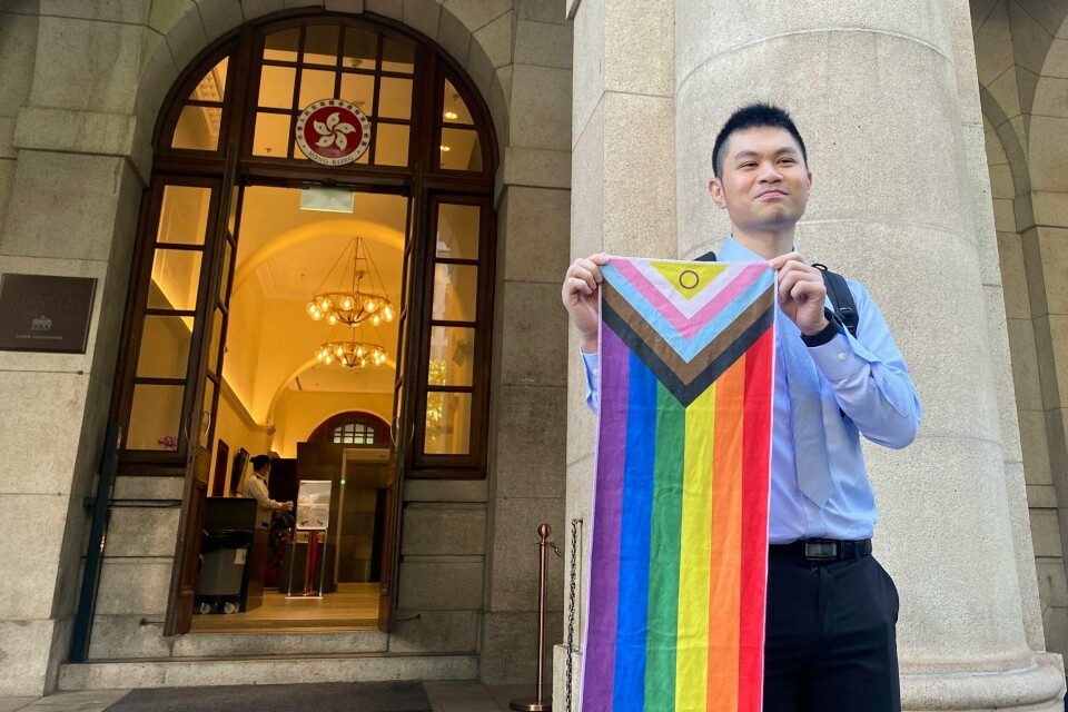 Nick Infinger poserer med et regnbueflagg etter å ha fått rettens medhold i at likekjønnede par skal ha tilgang på kommunale boliger i Hongkong. Nick Infinger poserer med et prideflagg etter å ha fått rettens medhold i at likekjønnede par skal ha tilgang på kommunale boliger i Hongkong. Foto: Alice Fung / AP / NTB