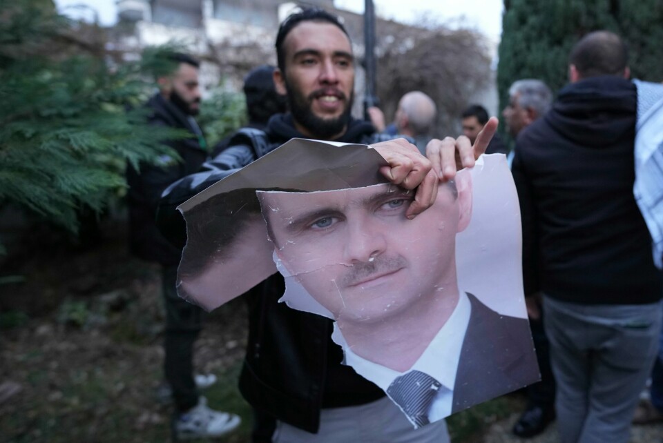 Syrere i mange land feirer at presidenten er fjernet, bildet er fra Beograd. Ifølge russiske nyhetsbyråer har Assad fått asyl i Russland. En mann river i stykker et portrett av Bashar al-Assad utenfor den syriske ambassaden i Beograd i Serbia. Foto: Darko Vojinovic / AP / NTB