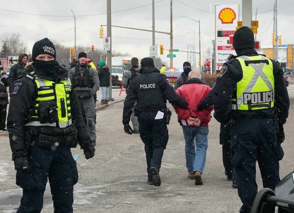 En demonstrant blir ledet bort av canadisk politi nær Ambassador Bridge mellom Detroit i USA og Windsor i Canada. En demonstrant blir ledet bort av canadisk politi nær Ambassador Bridge mellom Detroit i USA og Windsor i Canada. Foto: Nathan Denette / The Canadian Press via AP / NTB
