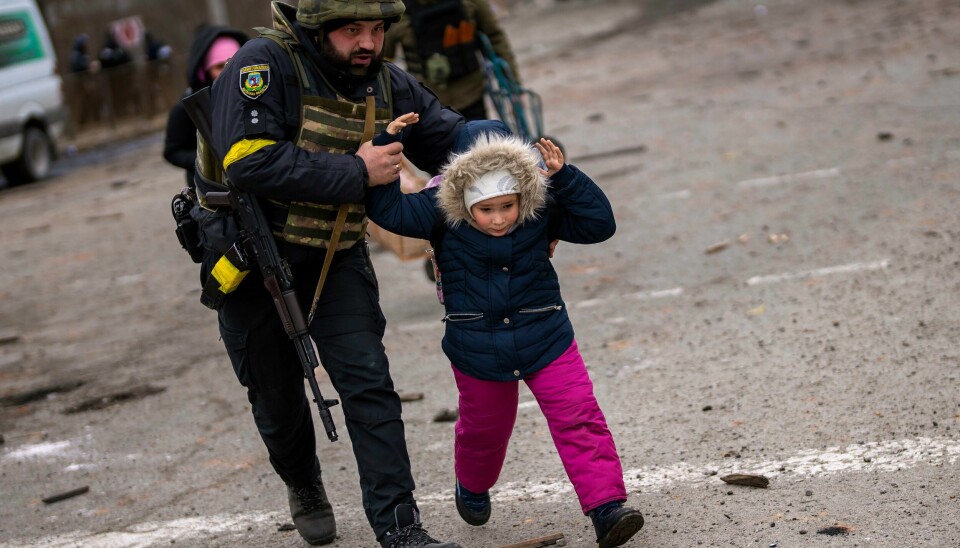 En ukrainsk politimann hjalp mandag en liten jente i sikkerhet under et artilleriangrep mot Irpin i utkanten av Kyiv. En ukrainsk politimann hjalp mandag en liten jente i sikkerhet under et artilleriangrep mot Irpin i utkanten av Kyiv. Foto: AP / NTB