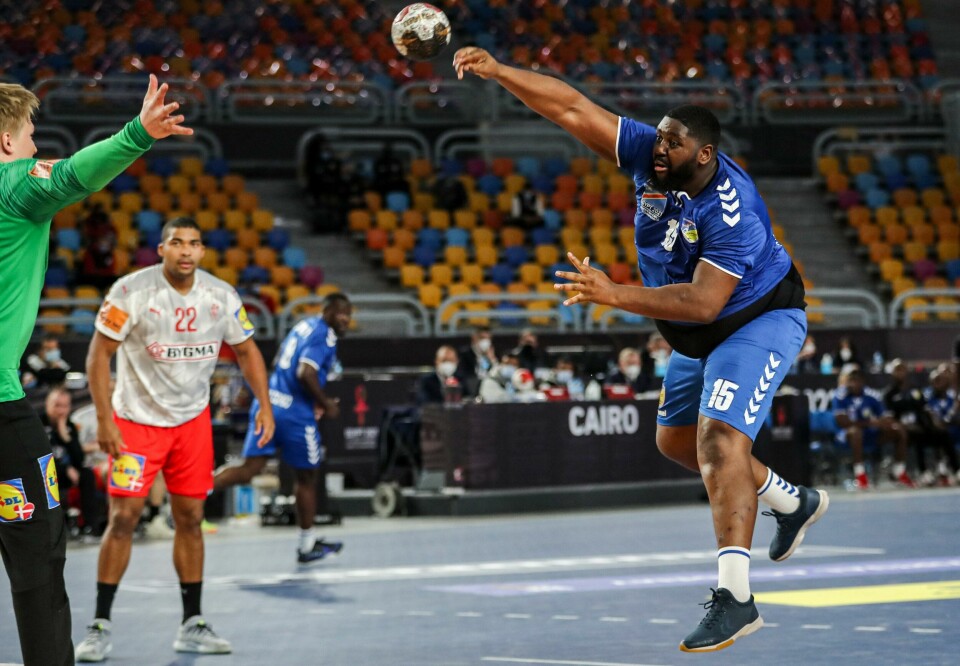 Kongos Gauthier Mvumbi (t.h) prøver seg med et skudd mot Danmark i Kairo søndag kveld. Democratic Republic of Congo's pivot Gauthier Mvumbi (R) attempts a shot during the 2021 World Men's Handball Championship match between Group D teams DR Congo and Denmark at the Cairo Stadium Sports Hall in the Egyptian capital on January 17, 2021. (Photo by MOHAMED ABD EL GHANY / POOL / AFP)