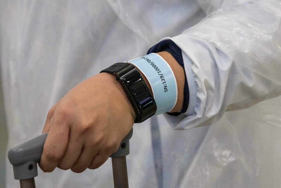 Kina har gått lengst i bruk av digitale verktøy mot koronasmitten. Her er en person utstyrt med et armbånd som er koblet til en app. Appen sporer hvor personer som er ilagt karantene befinner seg. Foto: Anthony Wallace/AFP