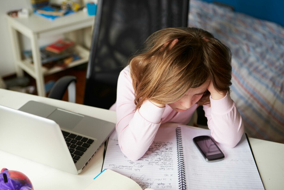 Media og myndigheter har vært opptatt av de yngste barna. Men Alarmtelefonen mener ungdommene har fått for lite oppmerksomhet. Girl Using Mobile Phone Instead Of Studying In Bedroom Sitting In Chair With Head In Hands