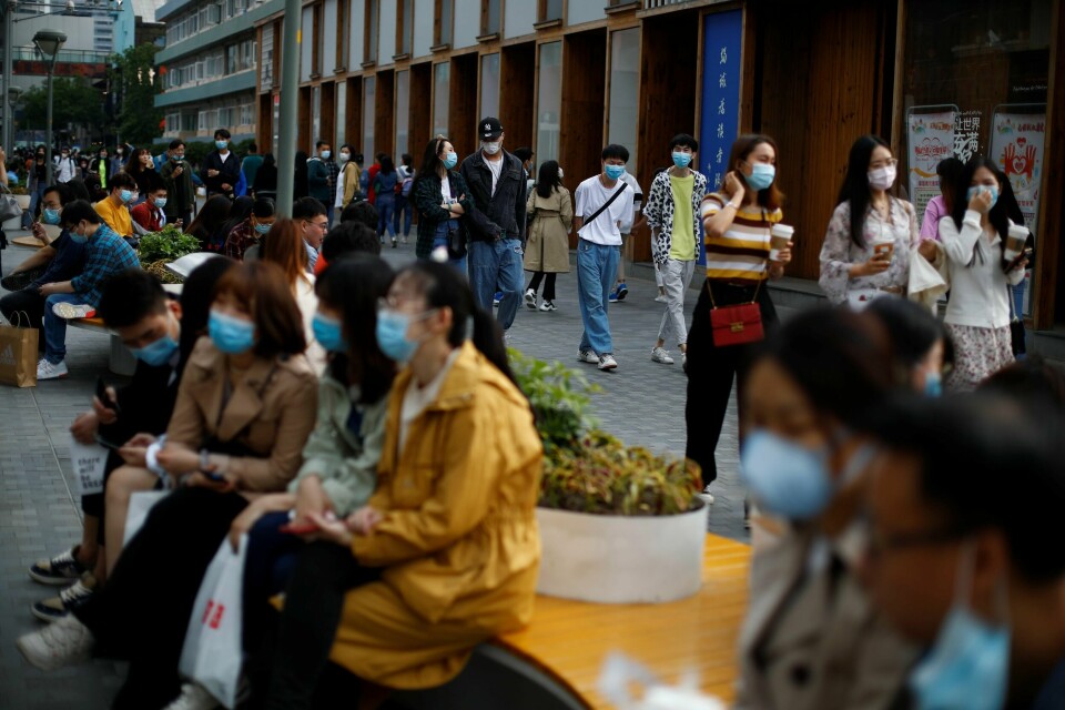 Det er tett mellom munnbindene, men dagliglivet er i stor grad tilbake i Kinas hovedstad Beijing. I resten av verden koronapandemien på langt nær under kontroll. Foto: Thomas Peter/NTB scanpix