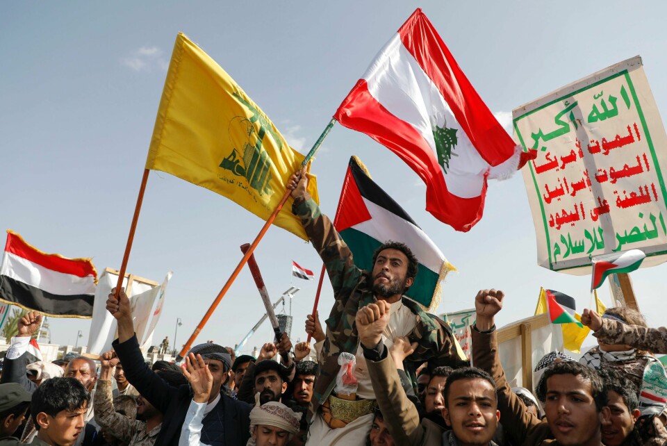 Houthi-tilhengere i hovedstaden Jemen viftet med flagget til både Libanon, Palestina, Jemen og Hizbollah da de demonstrerte mot Israel og USA fredag. På plakaten med arabisk skrift står det «Død over Israel og Amerika». Houthi-tilhengere i hovedstaden Jemen viftet med flagget til både Libanon, Palestina, Jemen og Hizbollah da de demonstrerte mot Israel og USA fredag. På plakaten med arabisk skrift står det «Død over Israel og Amerika». Foto: Osamah Abdulrahman / AP / NTB