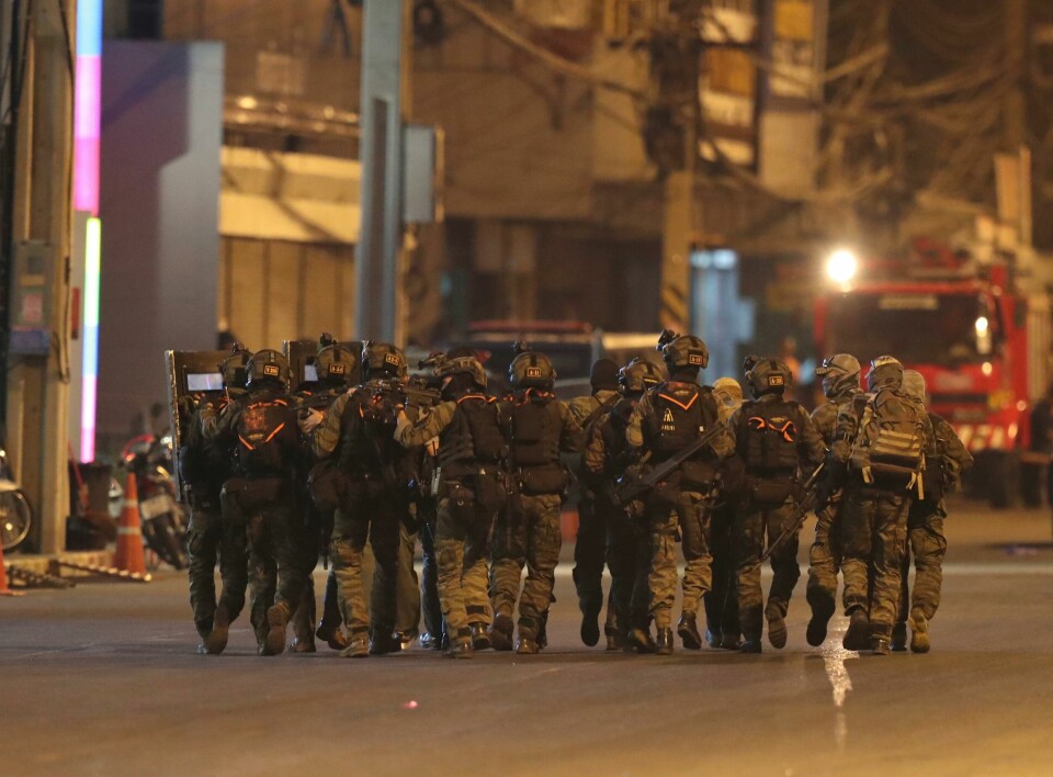Thailandske spesialstyrker utenfor kjøpesenteret Terminal 21 i Korat lørdag. A group of armed commando soldiers walk close together outside Terminal 21 Korat mall, in Nakhon Ratchasima, Thailand on Sunday, Feb. 9, 2020. A soldier who holed up in a popular shopping mall in northeastern Thailand shot multiple people on Saturday, killing at least 20 and injuring 31 others, officials said. (AP Photo/Sakchai Lalitkanjanakul)