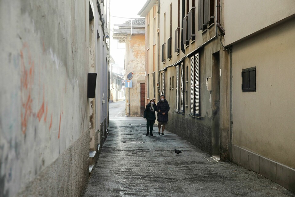 To kvinner med munnbind går gjennom en gate i byen Codogno i Nord-Italia. Two women wear masks as they walk in a street in Codogno, near Lodi, Northern Italy, Saturday, Feb. 22, 2020. A dozen towns in northern Italy are on effective lockdown after the new virus linked to China claimed a first fatality in Italy and sickened an increasing number of people. The secondary contagions have prompted local authorities in towns of Lombardy and Veneto to order schools, businesses, and restaurants closed, and to cancel sporting events and Masses. (AP Photo/Luca Bruno)