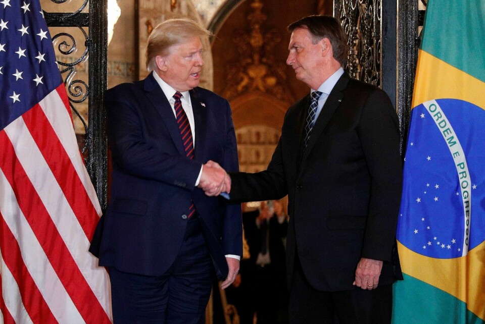 USAs president Donald Trump tar Brasils president Jair Bolsonaro i hånda under en middag i Florida 7. mars. Bolsonaro har ifølge en brasiliansk avis testet positivt på koronaviruset.