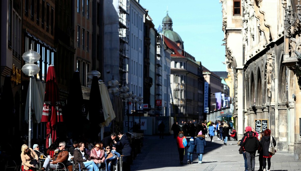 Folk nyter sola på en kafé i München søndag.