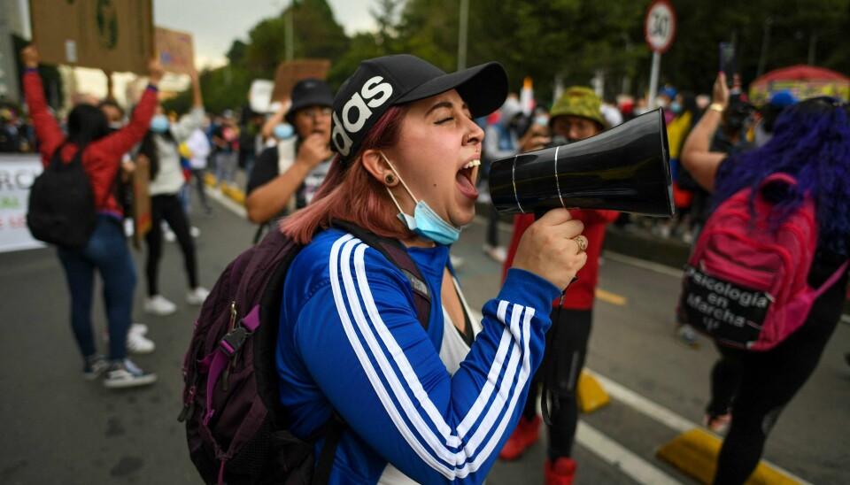 Folk protesterer mot myndighetene i Bogota 8. mai. Forslag om skatteøkninger har utløst de store demonstrasjonene i hovedstaden i Colombia. Folk protesterer mot myndighetene i Bogota i Colombia 8. mai. En kvinne roper i en megafon.