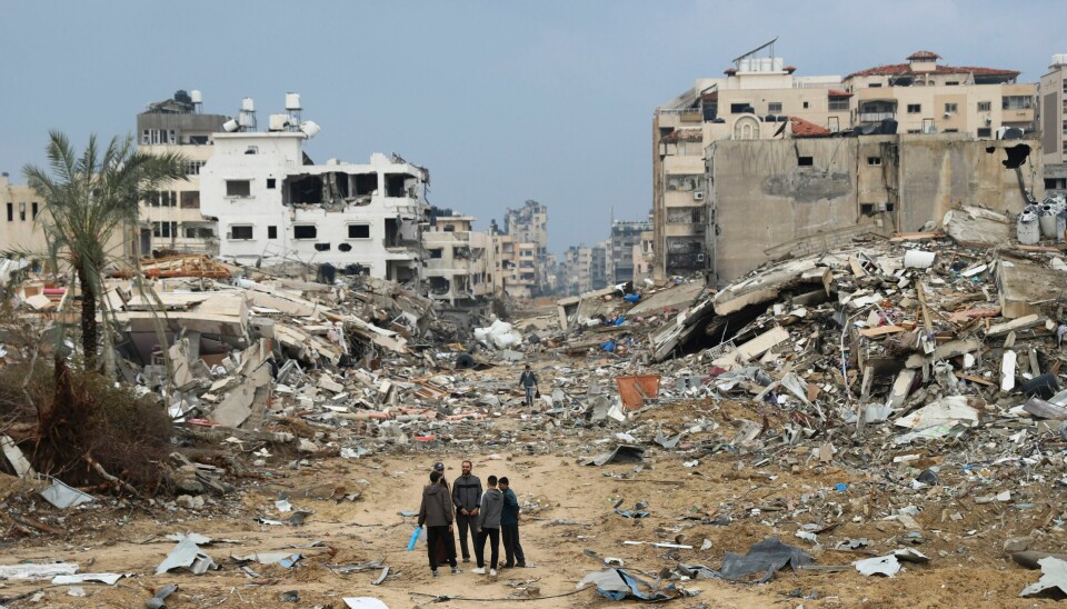 Palestinere foran bygninger ødelagt i israelske angrep i Gaza by. Human Rights Watch mener Israel gjør seg skyldig i krigsforbrytelser på Gazastripen. Palestinere står ved bygninger som har blitt ødelagt i israelske luftangrep i Gaza by. Foto: Mohammed Hajjar / AP / NTB