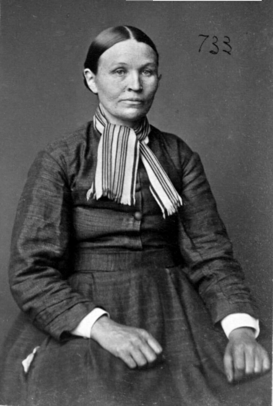 Fangeportrett av Mathildes mor, Christiane Bjørn. Damen med mørkt hår og midtskill sitter på en stol med hendene knyttet. Hun har på seg mørk kjole og stripete skjerf.