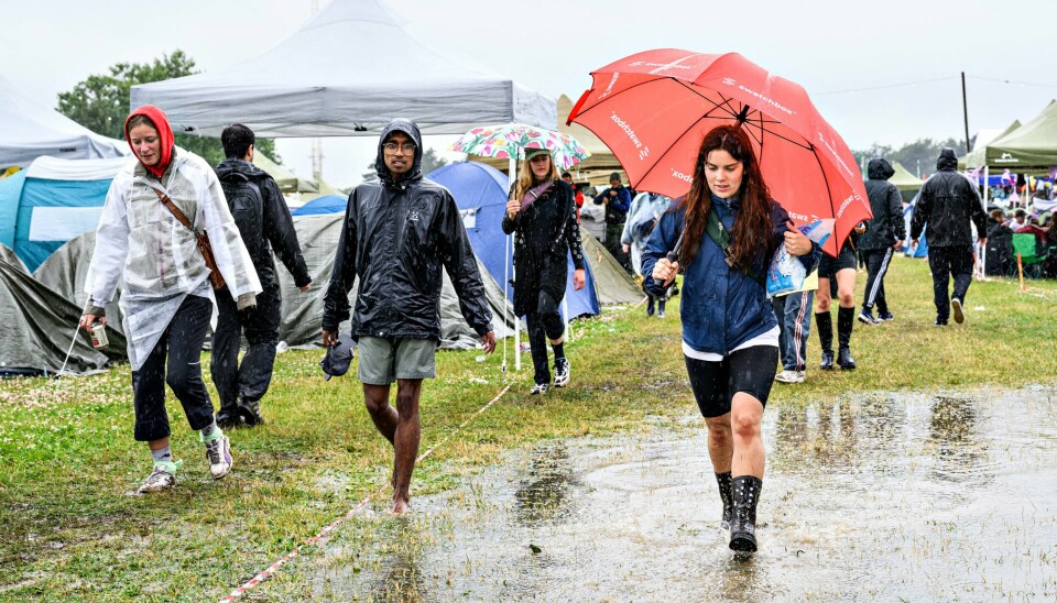 Det er vått på årets Roskilde-festival, og lørdag er det ventet mer uvær. Gummistøvler, regntøy og paraply er blitt årets festivalmote av ren nødvendighet på Roskilde, som er rammet av kraftig regnvær. Foto: Torben Christensen / Ritzau Scanpix / NTB