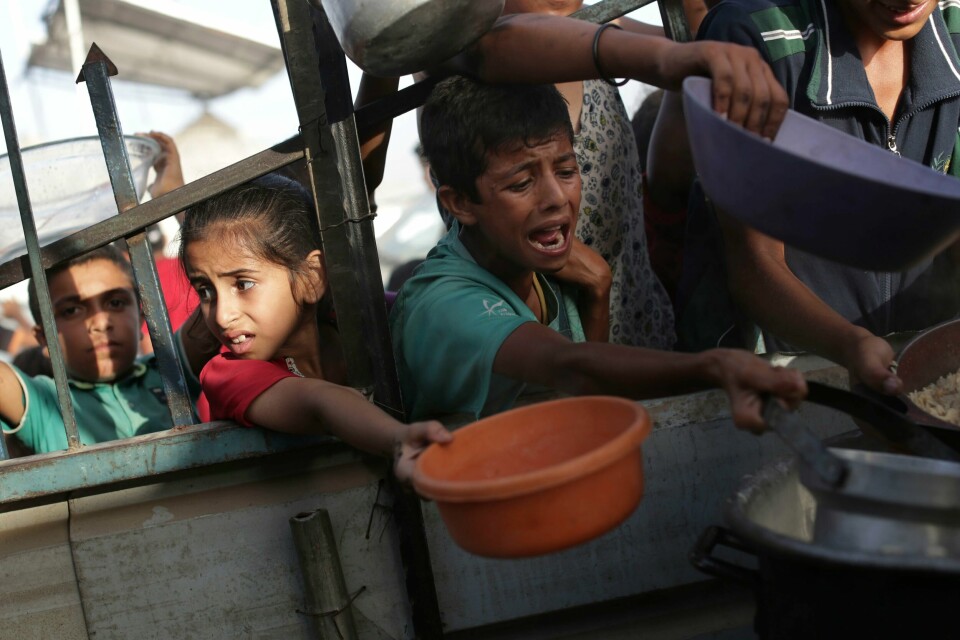 Palestinere venter på å få utdelt mat av hjelpearbeidere i Khan Younis. Det har i flere måneder blitt meldt om matmangel, og Verdens matprogram (WFP) anslår at 96 prosent av befolkningen i Gaza opplever akutt matusikkerhet. Palestinske barn får mathjelp i Khan Younis i forbindelse med id al-adha lørdag. I tillegg til at titusenvis er drept i Gaza-krigen, har et ukjent antall palestinere sultet i hjel som følge av krigen og manglende nødhjelpstilgang. Foto: Jehad Alshrafi / AP / NTB