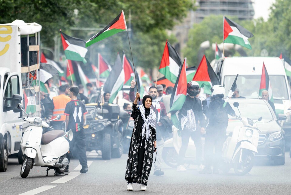 En kvinne vifter med et palestinsk flagg foran en pro-palestinsk bilkortesje i Berlin, fredag 2. august 2024. En kvinne vifter med et palestinsk flagg foran en propalestinsk bilkortesje i Berlin forrige fredag. Tirsdag ble en annen kvinne i den tyske hovedstaden dømt for å ha ytret et kjent propalestinsk slagord under en demonstrasjon i fjor. Foto: Fabian Sommer/dpa via AP / NTB