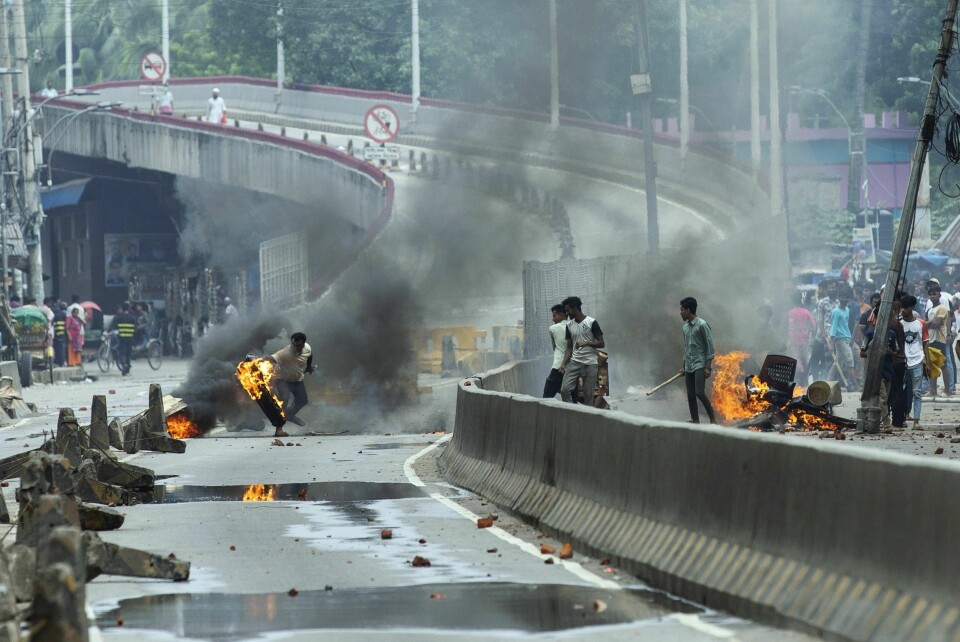Minst 109 personer ble drept i Bangladesh mandag, noe som betyr at denne dagen var den dødeligste siden uroen brøt ut i begynnelsen av juli. Bildet viser en demonstrant som kaster et brennende bildekk. Foto: Rajib Dhar / AP / NTB