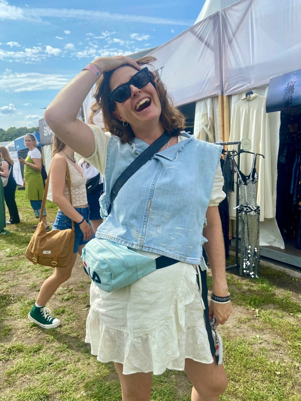 Sunniva Leishley Sandbu er fornøyd med dagens unike fangst. Kvinne smiler stort med en lysblå denimvest på foran Fretex-boden på Øyafestivalen.