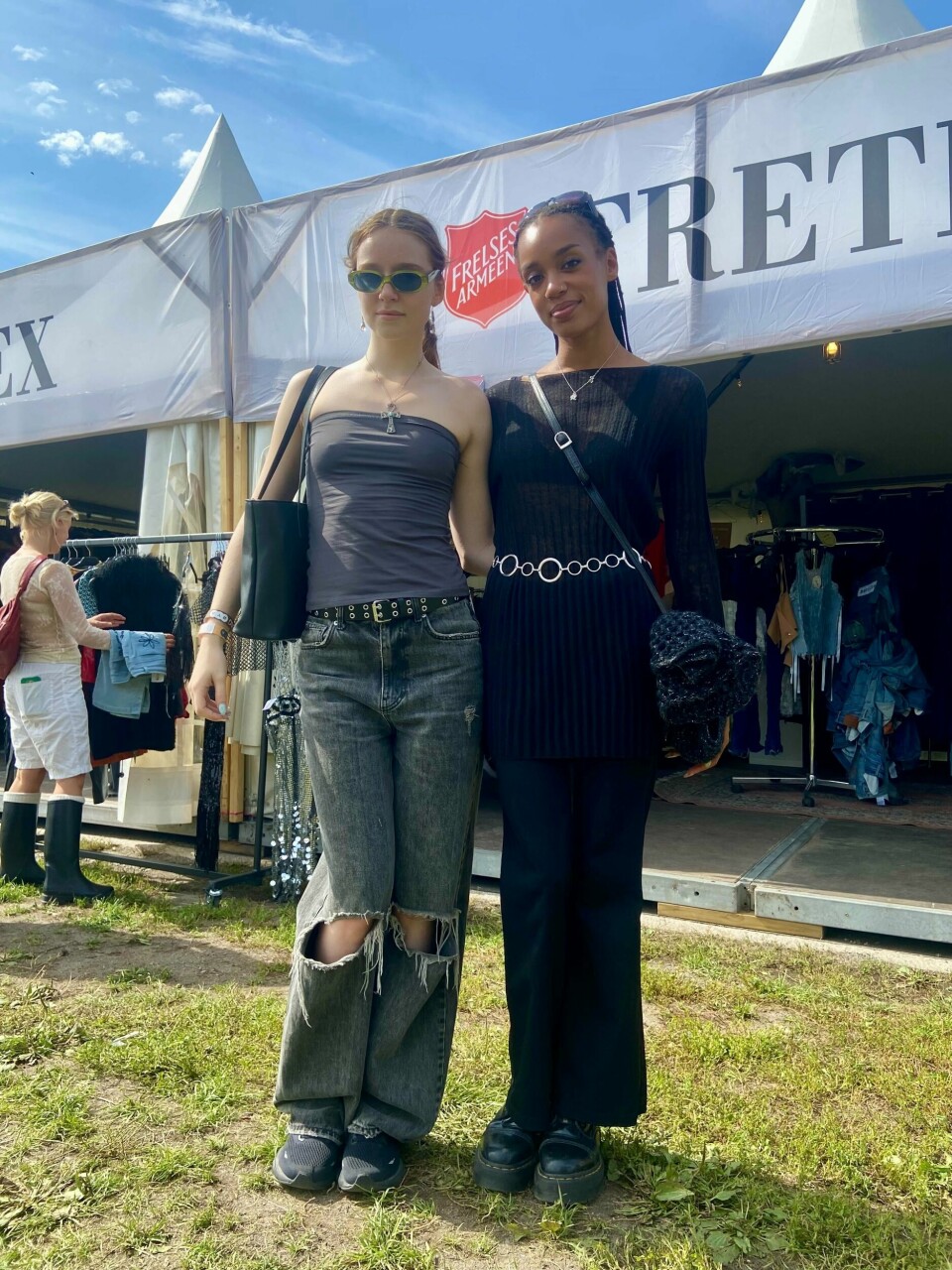 Anne Bredeli (tv.) og Naima Rashidi (th.) To jenter i kule klær står foran Fretex-teltet og poserer.