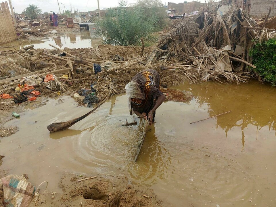 En kvinne leter gjennom flomvannet i nærheten av sitt ødelagte hjem i byen Abu Hamdan nord i Sudan 7. august. En kvinne prøver å redde noen av eiendelene sine fra sitt flomskadde hus i Abu Hamad i Nord-Sudan. Foto: Samira Hassan / AP / NTB