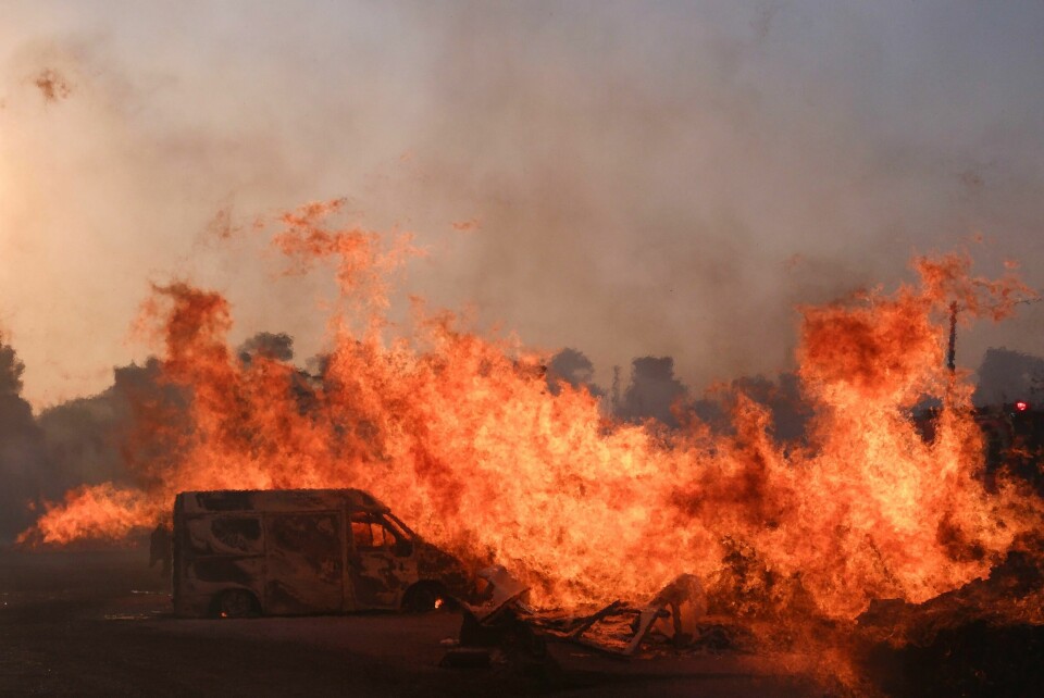 En bil slukes av flammene i en massiv brann nord for Aten. Brannen er nå slukket, melder greske myndigheter. En bil slukes av flammene i en massiv brann som herjer nord for Aten. Foto: Aggelos Barai / AP / NTB
