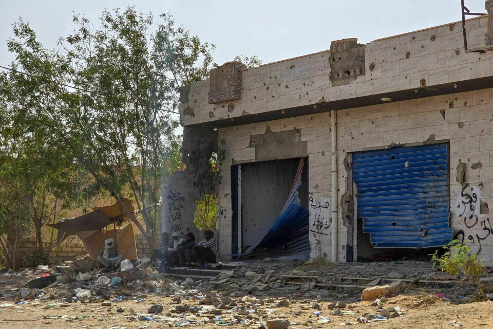 Folk sitter i skyggen bygning ødelagt av krigen i utkanten av hovedstaden Tripoli. Bildet er fra mai 2024. Folk sitter i skyggen bygning ødelagt av krigen i utkanten av hovedstaden Tripoli. Bildet er fra mai 2024.