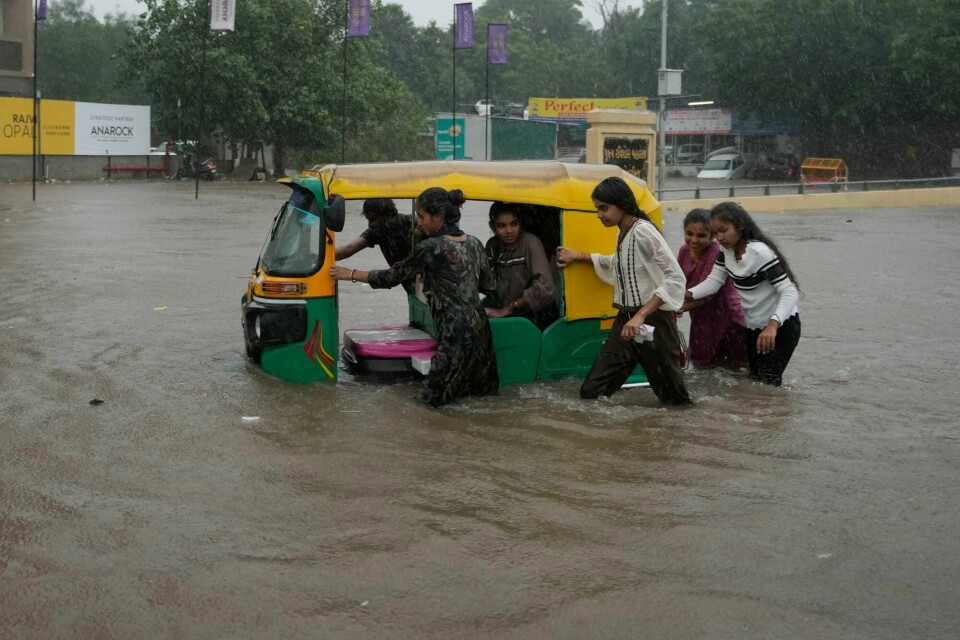 Kraftig regn har ført til flom i en rekke byer i delstaten Gujarat i India. Girls push an auto riksha through a flooded road during heavy rain in Ahmedabad, India, Monday, Aug. 26, 2024. (AP Photo/Ajit Solanki)