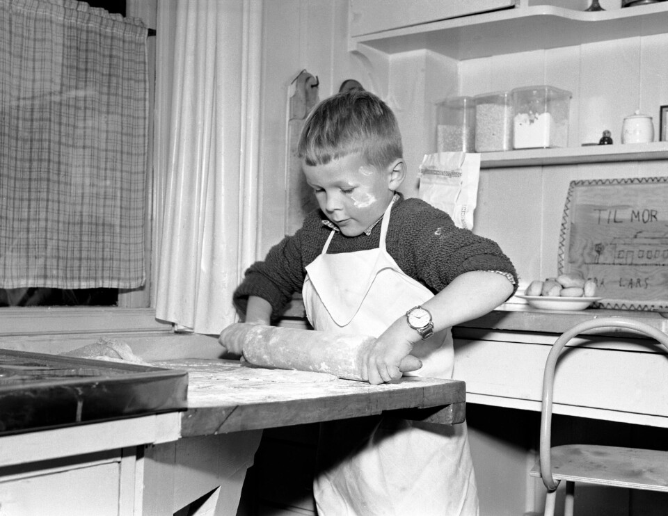 De som hadde en dyktig husholderske eller husmor ble på 1800-tallet forventet å servere 12-14 julekaker til julekvelden. OSLO 19541028 Barn baker julekaker. Liten gutt står på kjøkkenet med forkle og kjevler kakedeig.