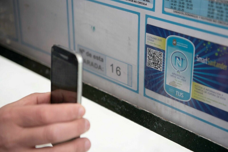 Her ser vi en person som bruker mobiltelefonen for å lese en QR-kode eller såkalt «smart sticker» på en busstopp i den spanske byen Santander, som også ynder å kalle seg en smartby. Foto: AFP Photo/Ander Gillenea