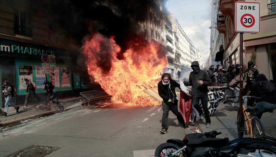 Demonstrasjonene i Paris gikk ikke rolig for seg. Demonstranter går forbi en søppelbrann startet under 1. mai-opptøyer i Paris, Frankrike. Foto: Lewis Joly / AP / NTB