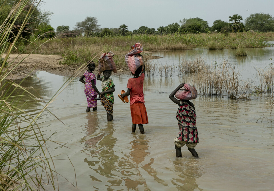 Tre år på rad har flommer skapt trøbbel og drevet tusenvis av mennesker på flukt i Sør-Sudan. Barn bærer poser på hodet mens de går over flomrammede jorder i Sør-Sudan.
