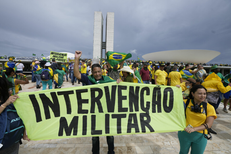 Flere demonstranter gikk rundt med banner hvor de ber om en militær intervensjon for å gjeninnsette den høyreradikale Jair Bolsonaro ved makten. Flere demonstranter gikk rundt med banner hvor de ber om en militær intervensjon for å gjeninnsette den høyreradikale Jair Bolsonaro ved makten. Foto: Eraldo Peres / AP / NTB