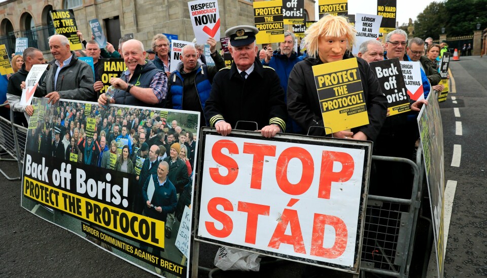 Demonstranter utenfor Hillsborough Castle i Nord-Irland i mai, under Boris Johnsons besøk. Den britiske regjeringen har lagt fram et lovforslag der den såkalte Nord-Irland-protokollen overstyres ensidig fra britisk side. EU reagerer skarpt, og det samme gjør regjeringen i Dublin og de i Nord-Irland som ønsker et forent Irland. Demonstranter utenfor Hillsborough Castle i Nord-Irland i mai, under Boris Johnsons besøk. Den britiske regjeringen har lagt fram et lovforslag der den såkalte Nord-Irland-protokollen overstyres ensidig fra britisk side. EU reagerer skarpt, og det samme gjør regjeringen i Dublin og de i Nord-Irland som ønsker et forent Irland. Foto: Peter Morrison / AP / NTB