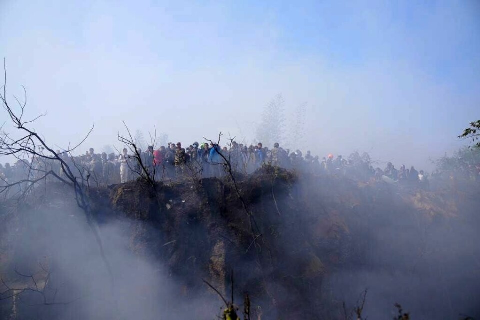 Innbyggere ser ned på vraket av flyet som styrtet i Pokhara i Nepal søndag. Innbyggere ser ned på vraket av flyet som styrtet i Pokhara i Nepal søndag. Foto: Yunish Gurung / AP / NTB