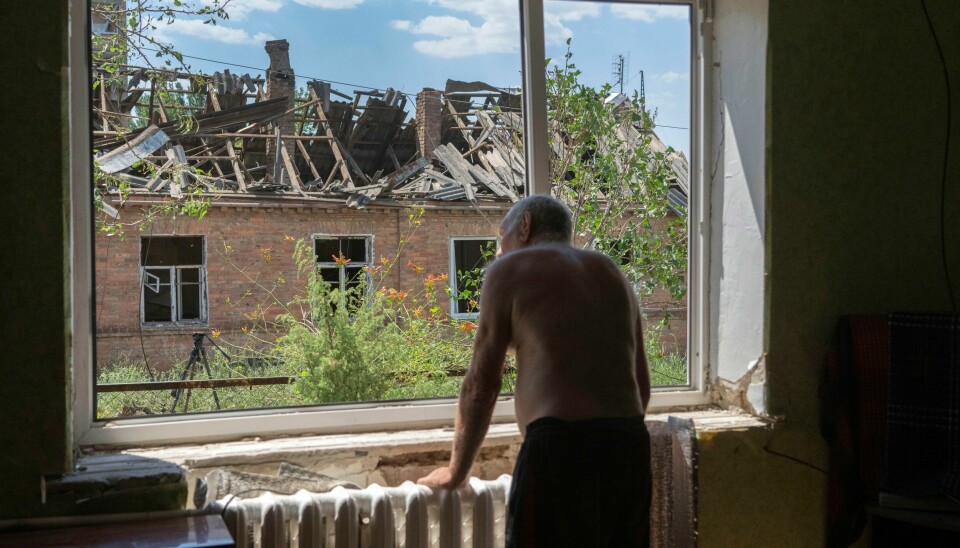 Victor Rosenberg, 81, ser ut på resultatene av russiske rakettangrep på Bakhmut i Donetsk-regionen, i juli 2022. Ukrainerne har forsvart seg mot russernes invasjon siden februar 2022. Victor Rosenberg (81) ser ut av vinduet etter at det ble ødelagt i et russisk angrep mot Bakhmut sentrum i juli i fjor. Arkivfoto: Efrem Lukatsky / AP / NTB