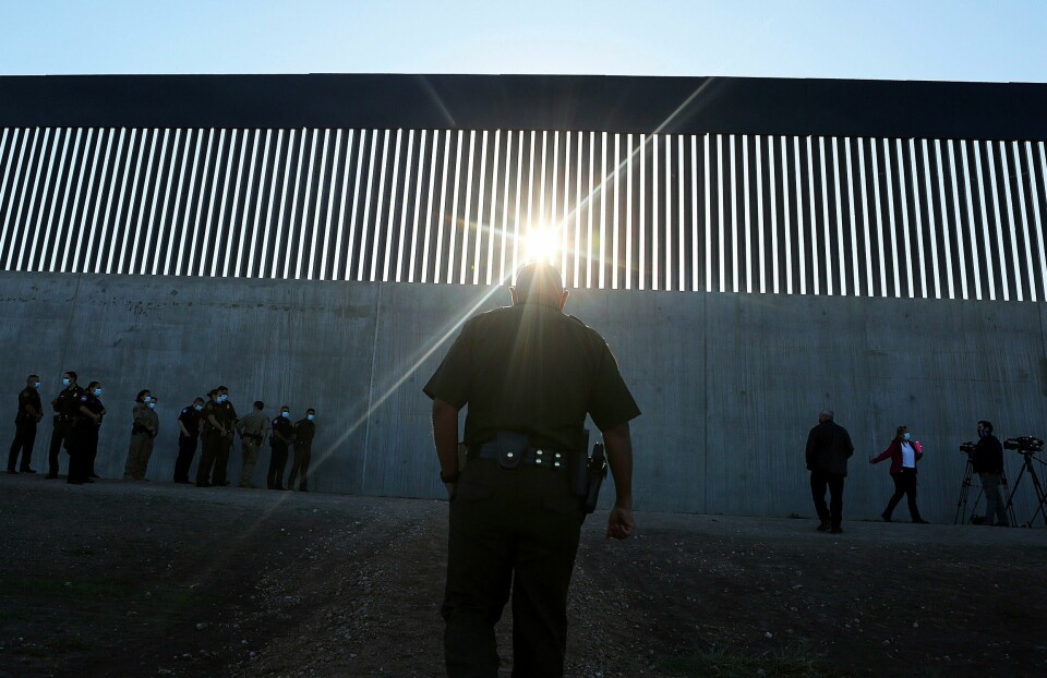 En amerikansk grensevakt står foran en ny del av muren i McAllen i Texas, på grensen mellom USA og Mexico. En amerikansk grensevakt står foran en ny del av muren i McAllen i Texas, på grensen mellom USA og Mexico. Foto: Joel Martinez / The Monitor / AP / NTB