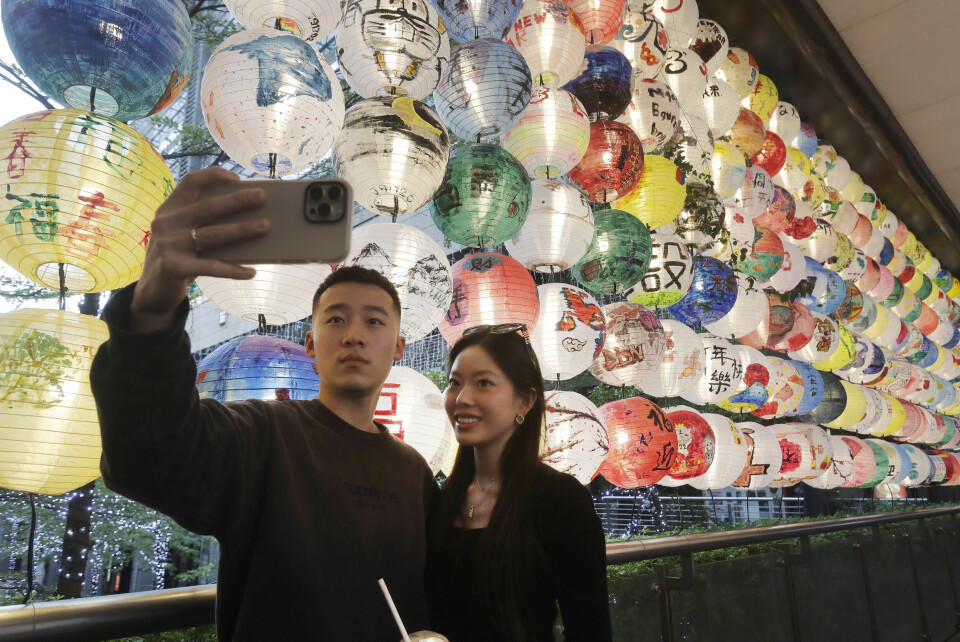 Turister poserer foran lanterner som er hengt opp for å feire kinesisk nyttår. Turister i Taiwan poserer foran lanterner i anledning kinesisk nyttår.