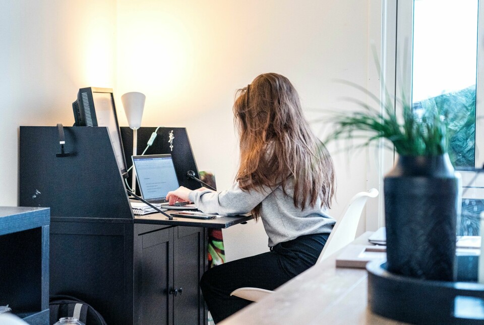 Flere som jobber hjemmefra sliter med å balansere jobb og privatliv viser et nytt forskningsstudie. Her er illustrasjonsfoto. Kvinne sitter med siden til kamera foran en pult med en pc. Hjemmekontor.