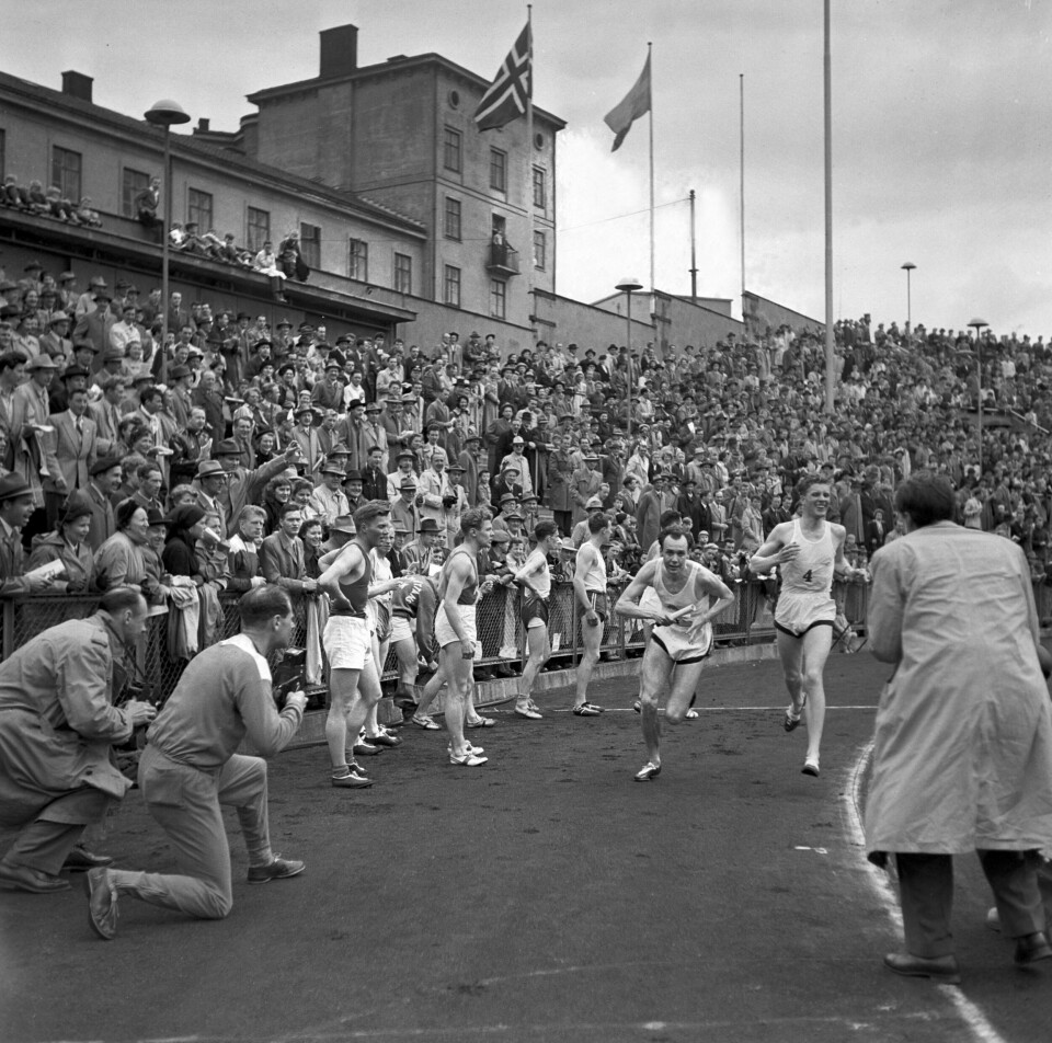 Vi er på Bislett i 1953. For første gang siden 1939 gikk et norsk lag til topps i Holmenkollstafetten. Tjalve vant 24 sekunder foran Tureberg fra Sverige. Her er siste veksling inne på Bislett stadion der Tjalves Erik Sarto har levert pinnen til Leif Ekeheim. Og fotografene er tett på. Vi er på Bislett i 1953. For første gang siden 1939 gikk et norsk lag til topps i Holmenkollstafetten. Tjalve vant 24 sekunder foran Tureberg fra Sverige. Her er siste veksling inne på Bislett stadion der Tjalves Erik Sarto har levert pinnen til Leif Ekeheim. Og fotografene er tett på.