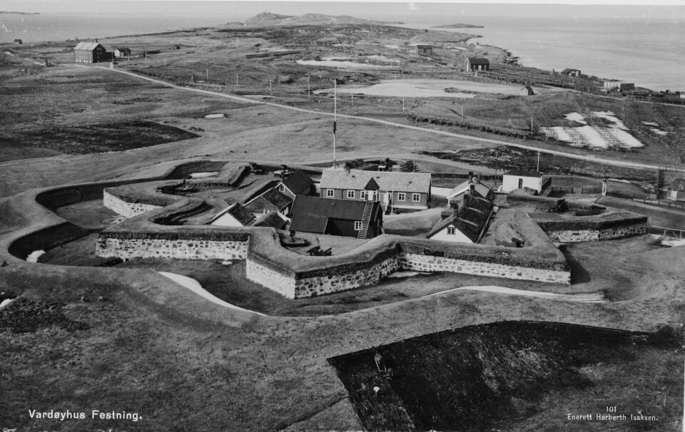 1662 ble ekteparet Ambrosius og Anna Rhodius dømt til æresløshet og forvisning til Vardøhus festning i Vardø, Øst-Finnmark. De åttekantete festningsvollene ble bygget først på 1730-talet. Flyfoto som viser flere bygninger innenfor murene og havet ses i bakgrunnen.
