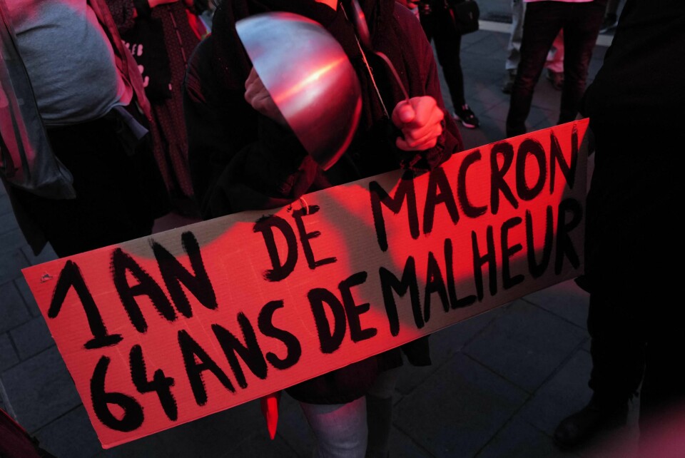 En demonstrant holder opp et skilt med teksten «Ett år med Macron, 64 år med ulykke» i en protest i Nice. Kjernen i den nye pensjonsreformen er at pensjonsalderen heves fra 62 til 64 år. A Demonstrator holds a sign reading 'One year of Macron, 64 years of unhappiness' and bashes a pan during a pan-banging protest in Nice, southeastern France on April 24, 2023, as part of a nationwide protest against French President Emmanuel Macron one year anniversary's reelection. (Photo by Valery HACHE / AFP) En demonstrant holder opp et skilt med teksten «Ett år med Macron, 64 år med ulykke» i en protest i Nice.