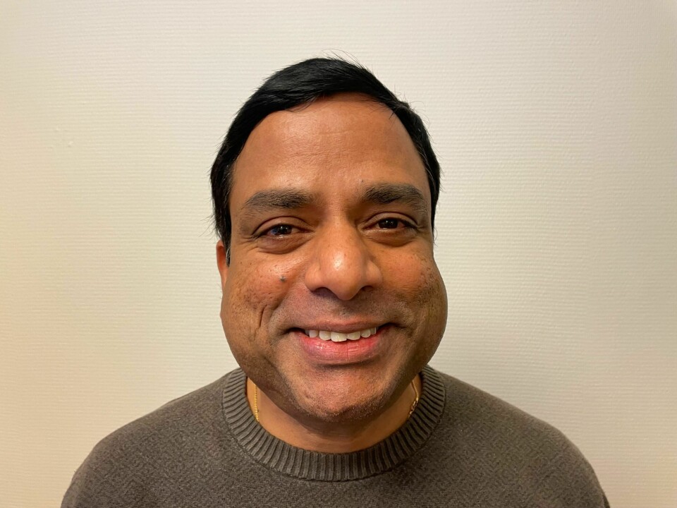 Rajeshwaran Subramaniam har jobbet som renholder i 26 år. Mann i 40-årene står foran en vegg. Han har svart hår og er iført en grå genser.