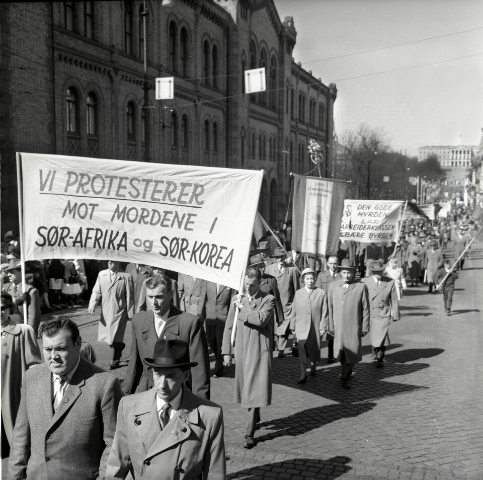 1. mai-toget i 1960 på Karl Johans gate med parolen «Vi protesterer mot mordene i Sør-Afrika og Sør-Korea». Hundrevis av demonstranter går i tog.