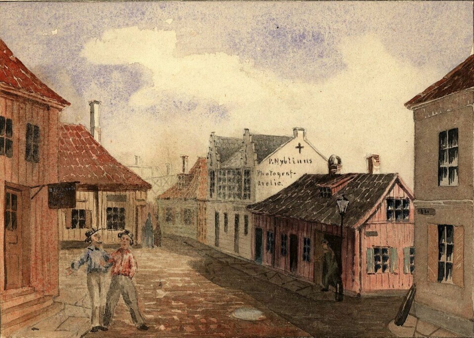 Lobinsky og sangerselskapet hans opptrådte blant annet i Vognmannsgata i Christiania. Her fra 1866. Maleri av to menn i en gate med brostein.