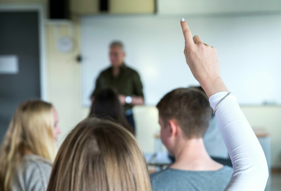 Vi må tørre å si nei til elevene, skriver innleggsforfatter. Tenåringer. Lærer og elever i klasserom. Undervisning pågår. Lærer underviser. Ser kun bakhodet til en jente som rekker opp hånda, hvit genser og hvit neglelakk.