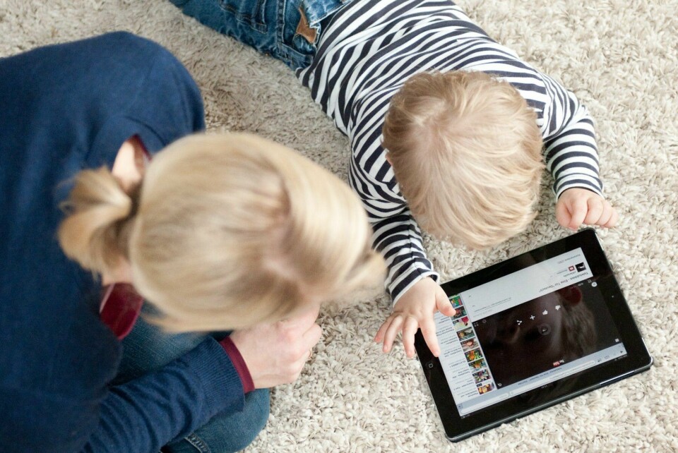 – Mange autister lærer dette på en annen måte, og min sønn er en såkalt Gestalt Language Learner. Barnet mitt skal nå få en iPad som hjelper han med kommunikasjon – fantastisk, skriver Kristin Marie Veum. Illustrasjonsbilde. Mor og sønn ligger på gulvet og ser på en ipad.