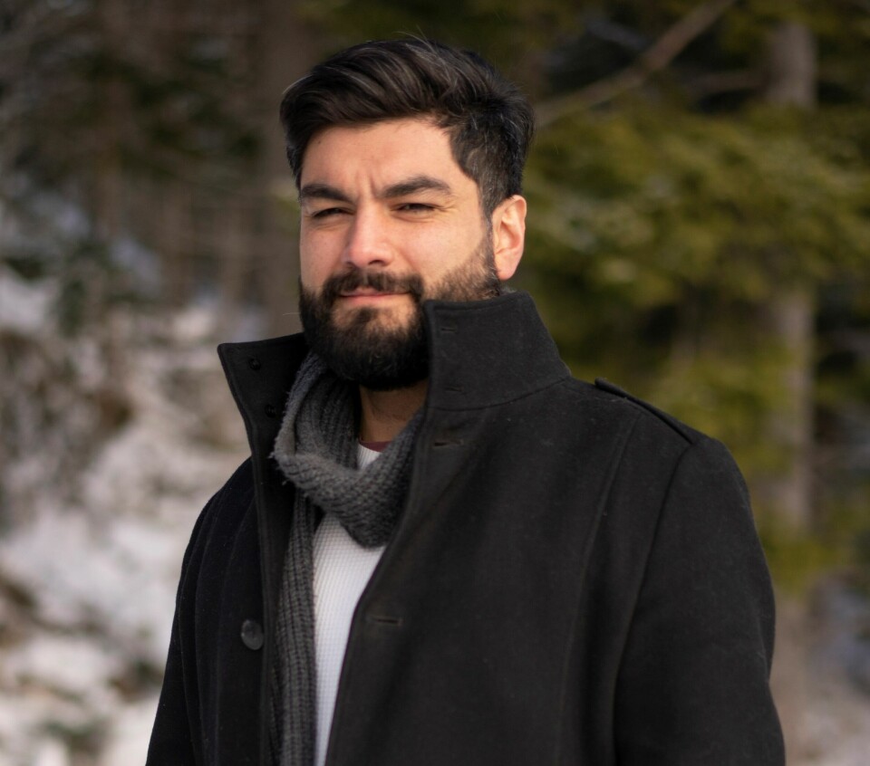 Luis Lautaro Espinoza Mann med svart kort hår, svart kort skjegg og bart. Siler svakt til kamera. Svart kåpe grått skjerf.