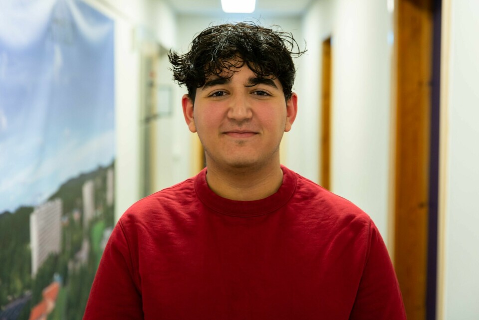 Ahmet Titrek, styremedlem unge Venstre Ung gutt meg tyrkisk utseende, svart hår og smiler med munnen lukket. Rød genser.